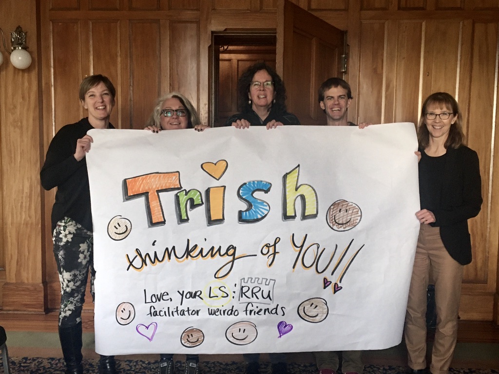 image of 4 people holding a sign that says Trish! Thinking of You!